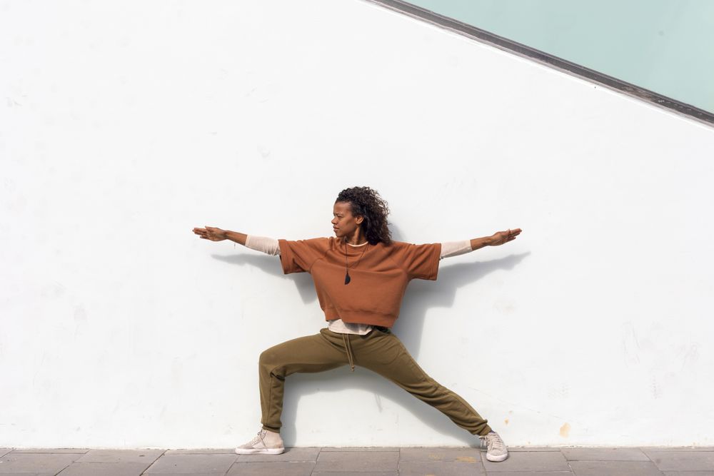 Woman in sportswear stretching before running against wall