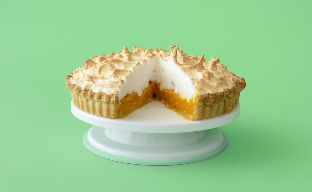 Lemon meringue cake isolated on a green background