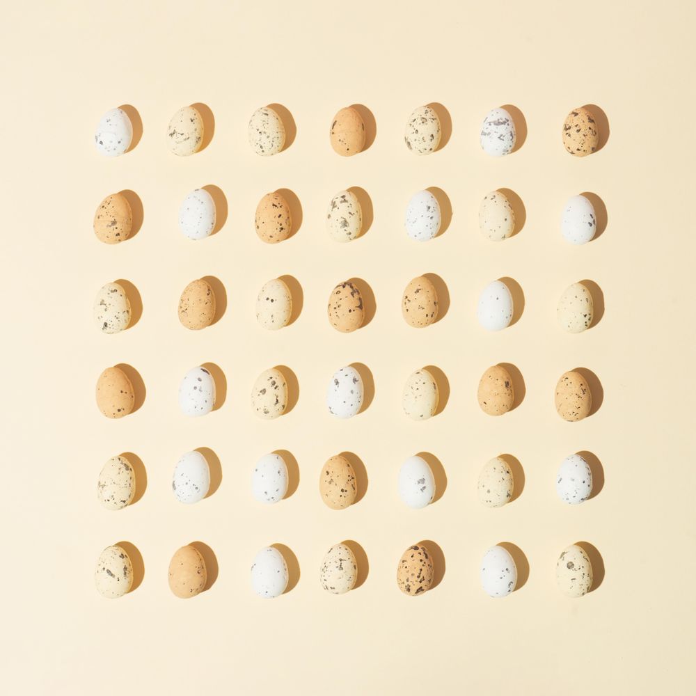 Speckled eggs  in rows on pastel yellow background