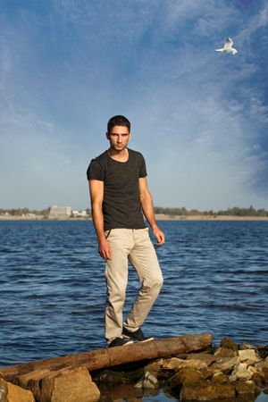 Male standing up on rocks surrounding a lake