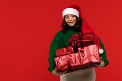 Woman looking down at pile of wrapped Christmas gifts.