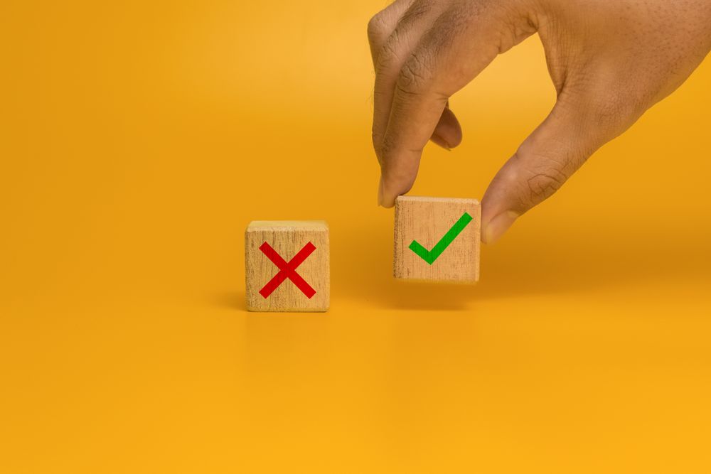 male hand put a wooden blocks with cross and checkmark symbol isolated on orange background