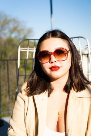 Portrait of young woman in round sunglasses outside