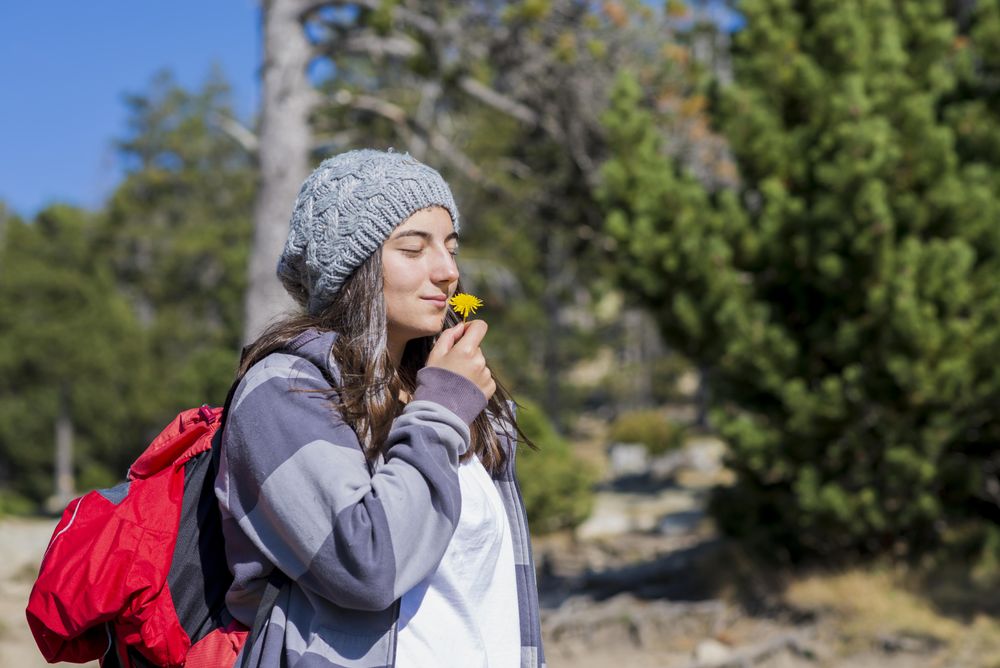 Young woman with eyes closed enjoying the smell of a flower in the forest