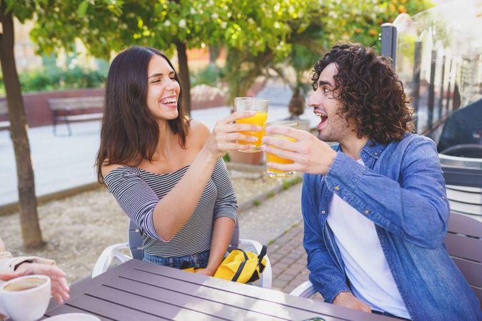 Man and woman toasting with their orange juice outside