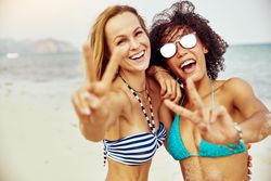 Two happy fit friends posing at the beach together