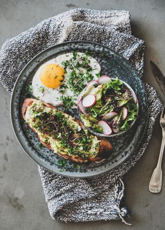 Avocado toast on sourdough bread with herbs and sprouts, on cloth napkin