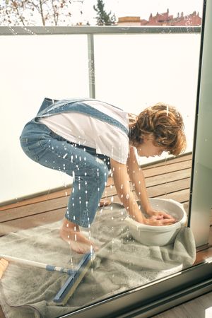 Boy washing windows at home