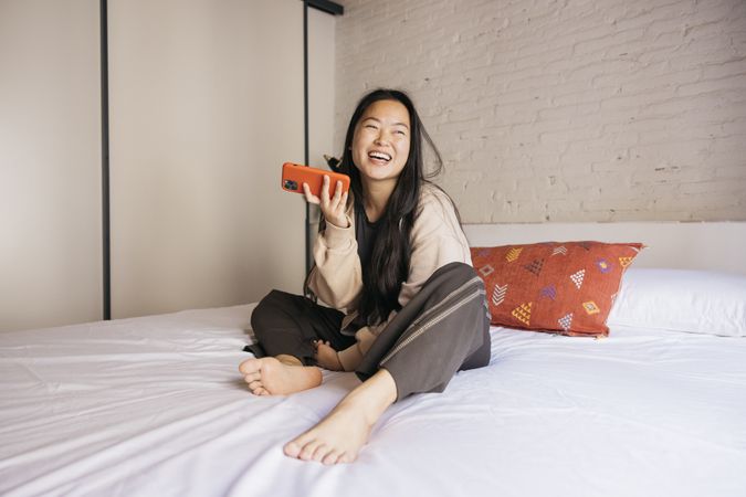 Young female using a phone on bed