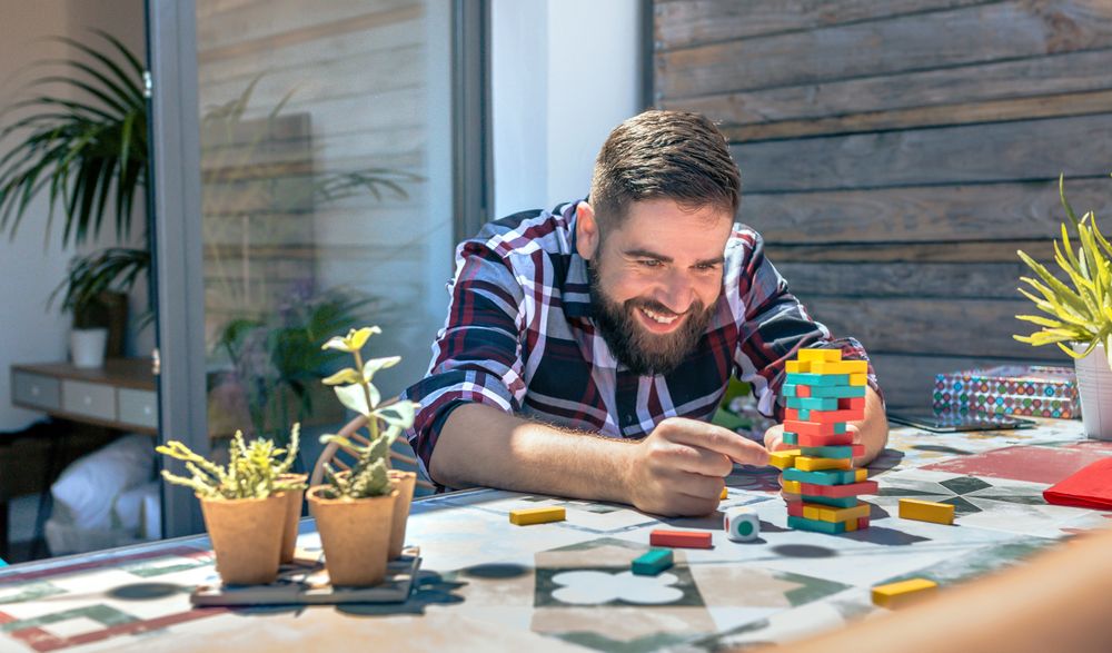 Bearded man catching jenga game piece in rooftop party