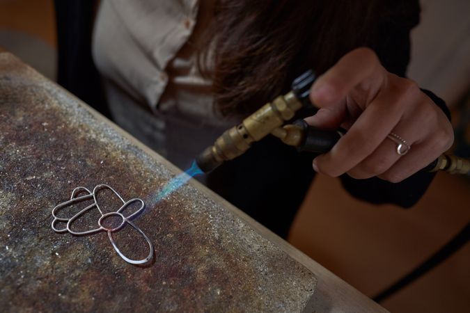 Woman making decorative handmade accessory with gas burner