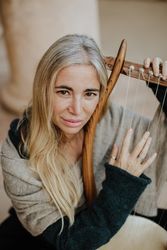 Romantic female musician playing lyre in terrace