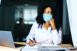 Calm woman wearing a facemask while working on documents 5waLZb