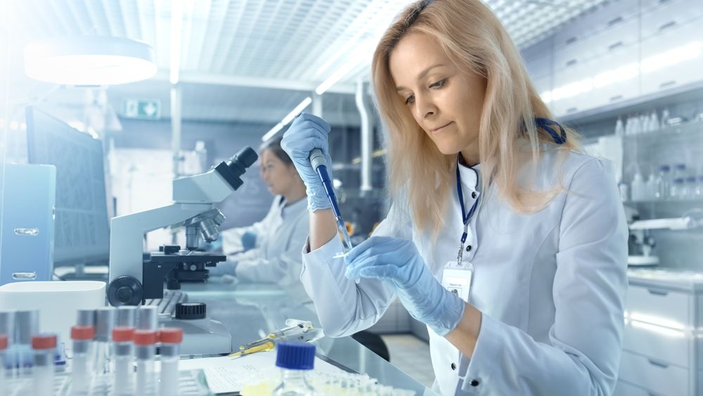 Female Research Scientist Uses Micropipette Filling Test Tubes in a Big Modern Laboratory.