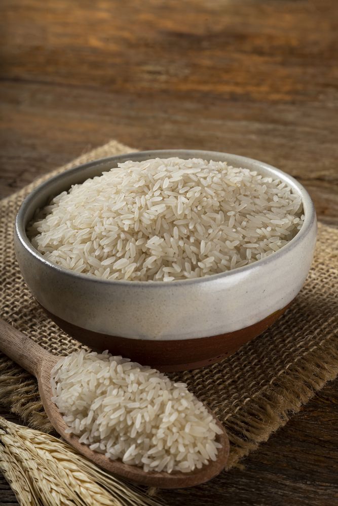 Rice in a ceramic bowl on brown wooden background.