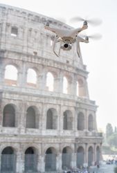 Unmanned Aircraft System Quadcopter Drone UAV In The Air Near The Colosseum In Rome.