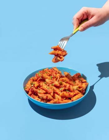 Penne pasta with spicy tomato sauce on a blue background