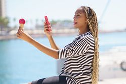 Female using phone to picture ice cream cone on the waterfront