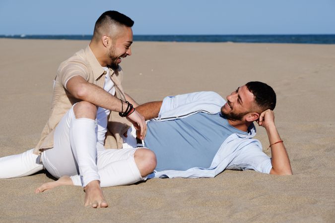 Affectionate gay couple relaxing on beach