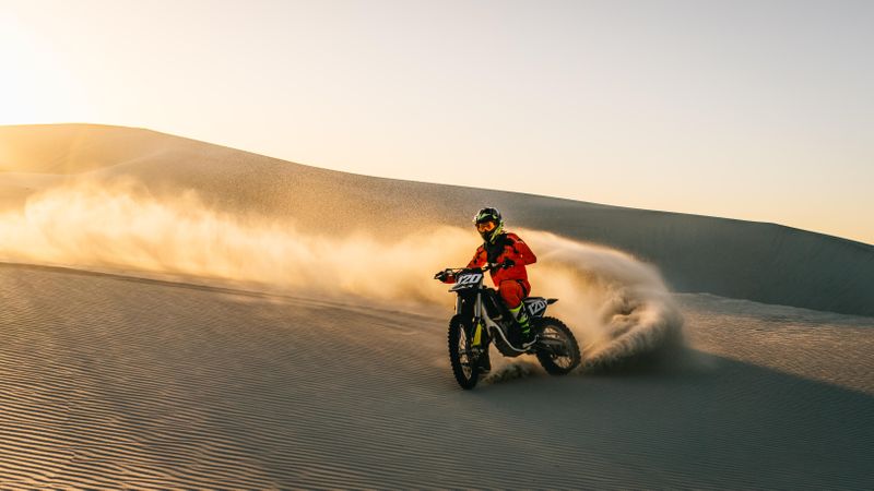 Dirt bike off roading on sand dunes in desert