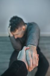 Unrecognizable man with problems receiving help from woman holding her hand