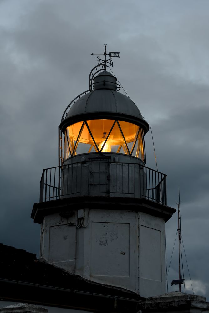 Shining lighthouse against cloudy sky
