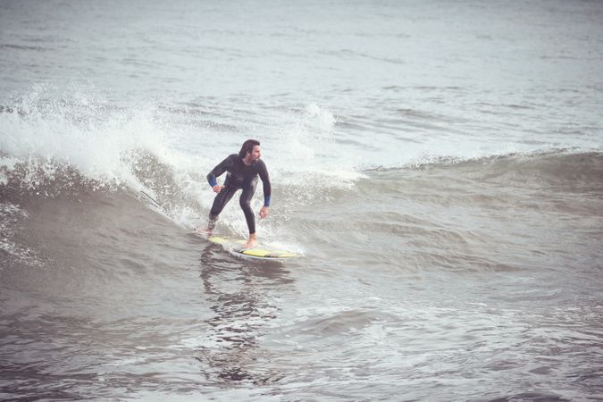 Surfer in wetsuit riding on wave on surfboard in ocean