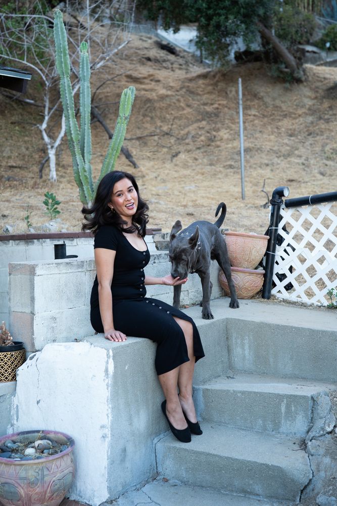 Woman smiling and looking at camera while petting her dog