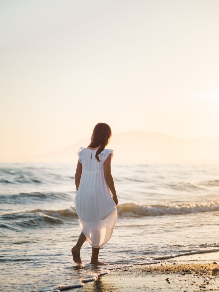 Adorable girl walking on seaside at sunset