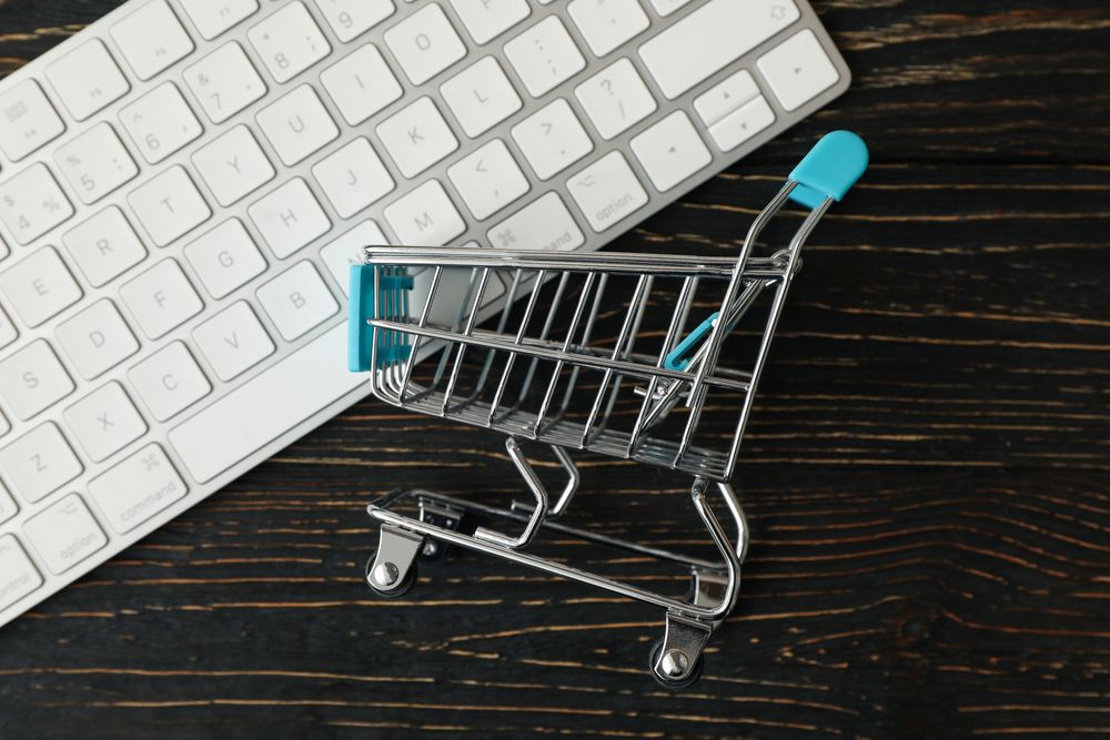 Shop cart and keyboard on wooden background
