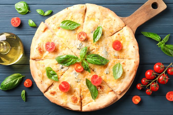 Cheese pizza, tomatoes and olive oil on wooden background, top view