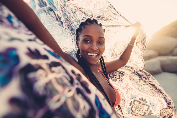 African young female on beach with a scarf looking at camera and smiling