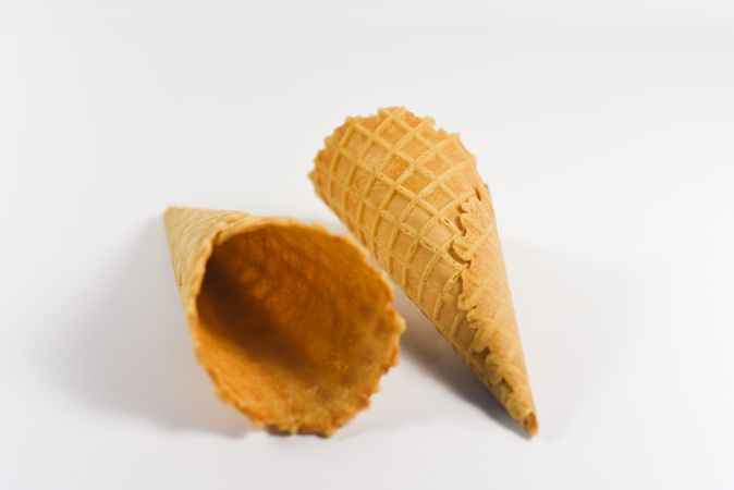Two empty waffle cones lying on plain table