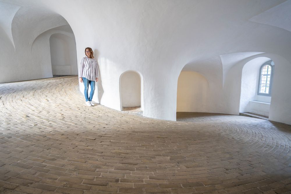 Casual woman leaning on wall in spacious gallery with windows