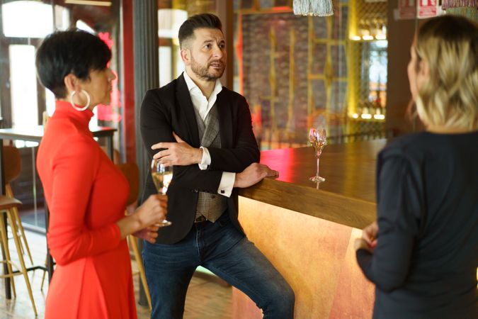 Three well dressed friends enjoying drinks together in bar