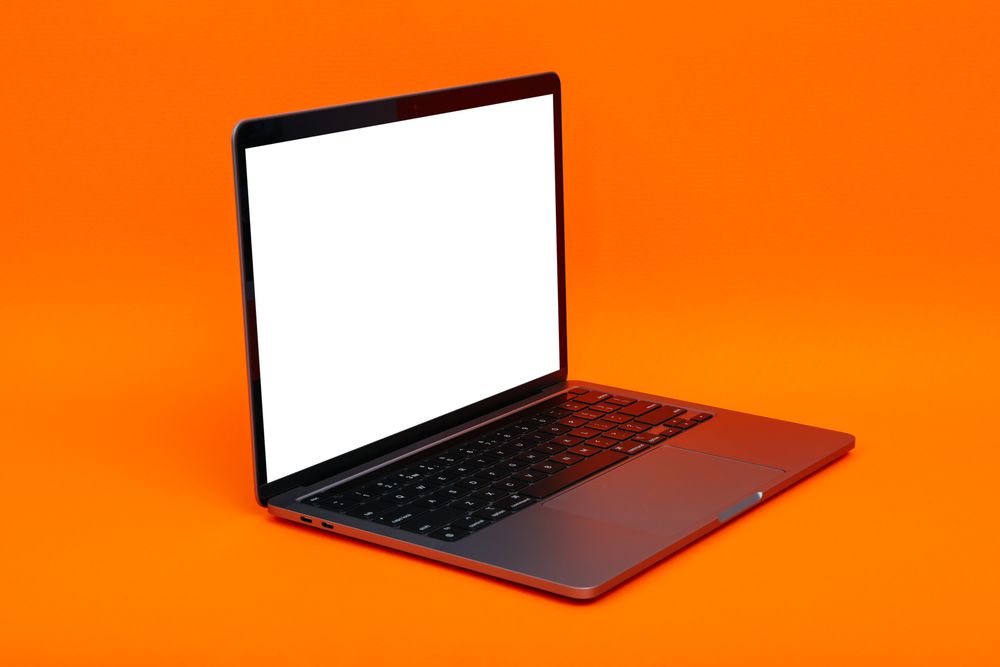 Laptop at angle with mockup screen in orange studio