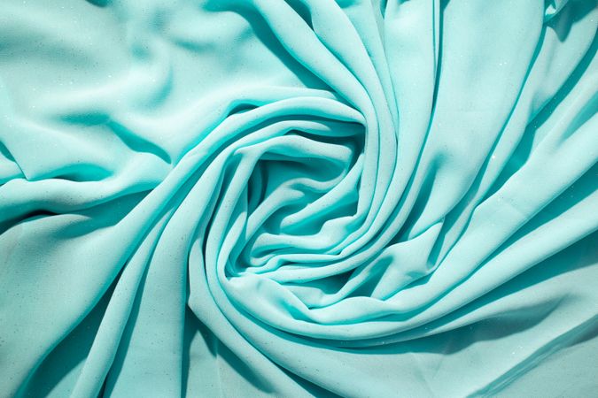 Spiral Twisted Turquoise wavy crumpled fabric with little sparkling dust, texture and  background.