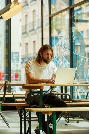 man sitting at table and typing on laptop