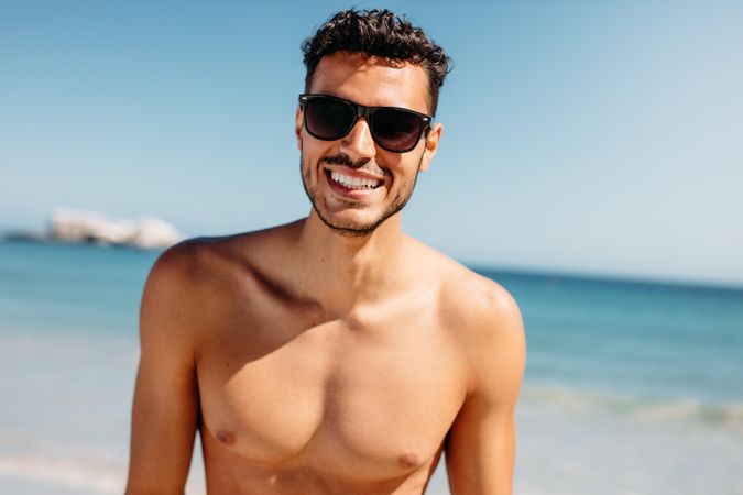 Close up of a shirtless man standing at the beach having fun