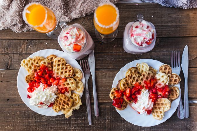 Appetizing waffles with jam and tasty drinks on tray on bed