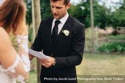 Handsome young groom reading wedding vows from a paper 4Z1JN5