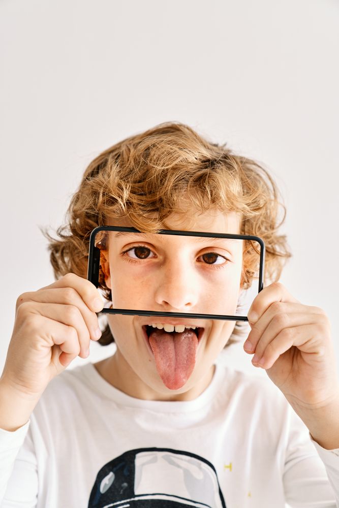 Child posing with his mobile phone and photos made of parts of his face