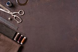 Sewing kit with thread, scissors, ruler on brown background