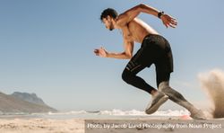 Fast runner on a beach with sand lifting off his shoes 43R8O5