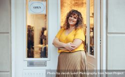 Beautiful curvy woman standing at entrance door of her clothing store 5rYAl0