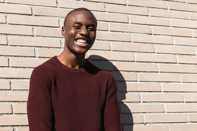 Happy young Black male standing near billet wall