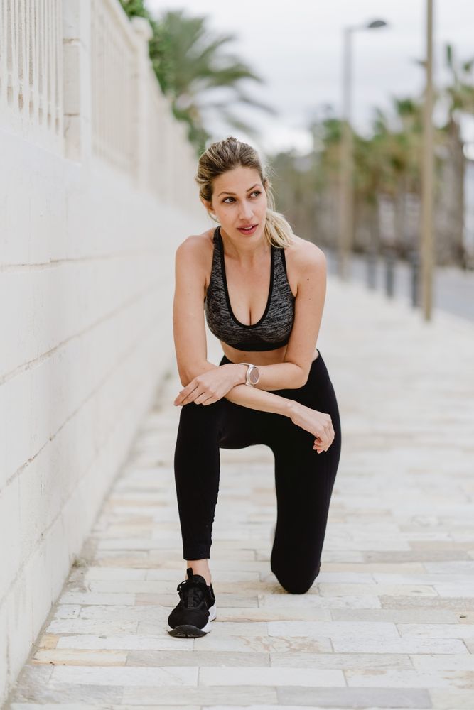 Satisfied sportswoman in active clothing smiling while exercising
