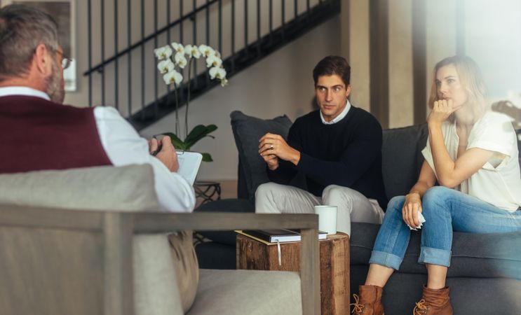 Married couple sitting on sofa and talking to therapist