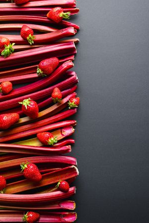 Rhubarb and strawberries on dark table