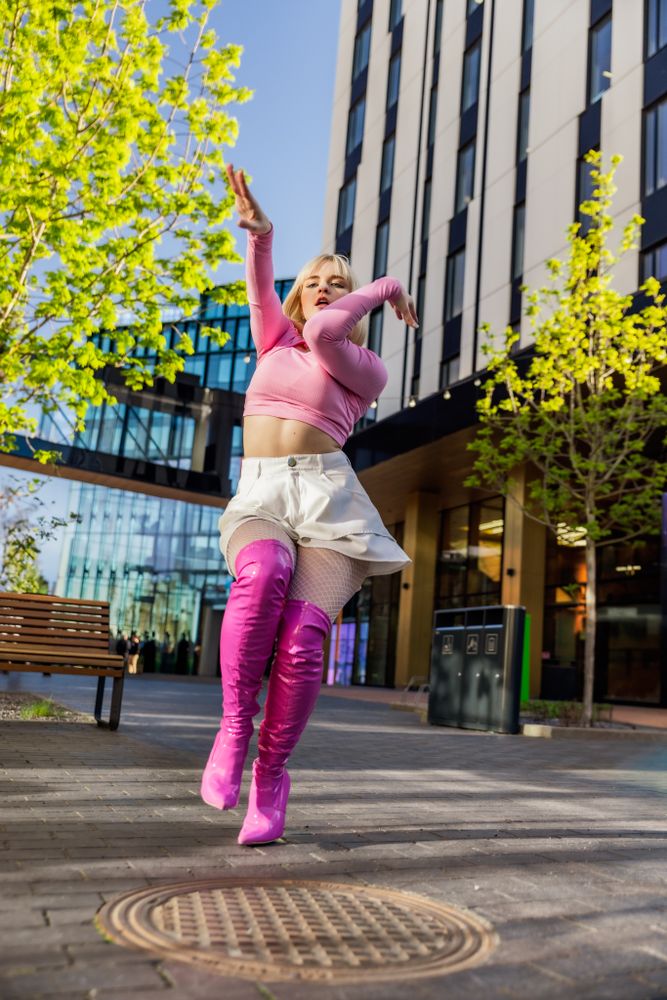 Fashionable Young Woman Wearing Pink Outfit And Voguing On City Street.